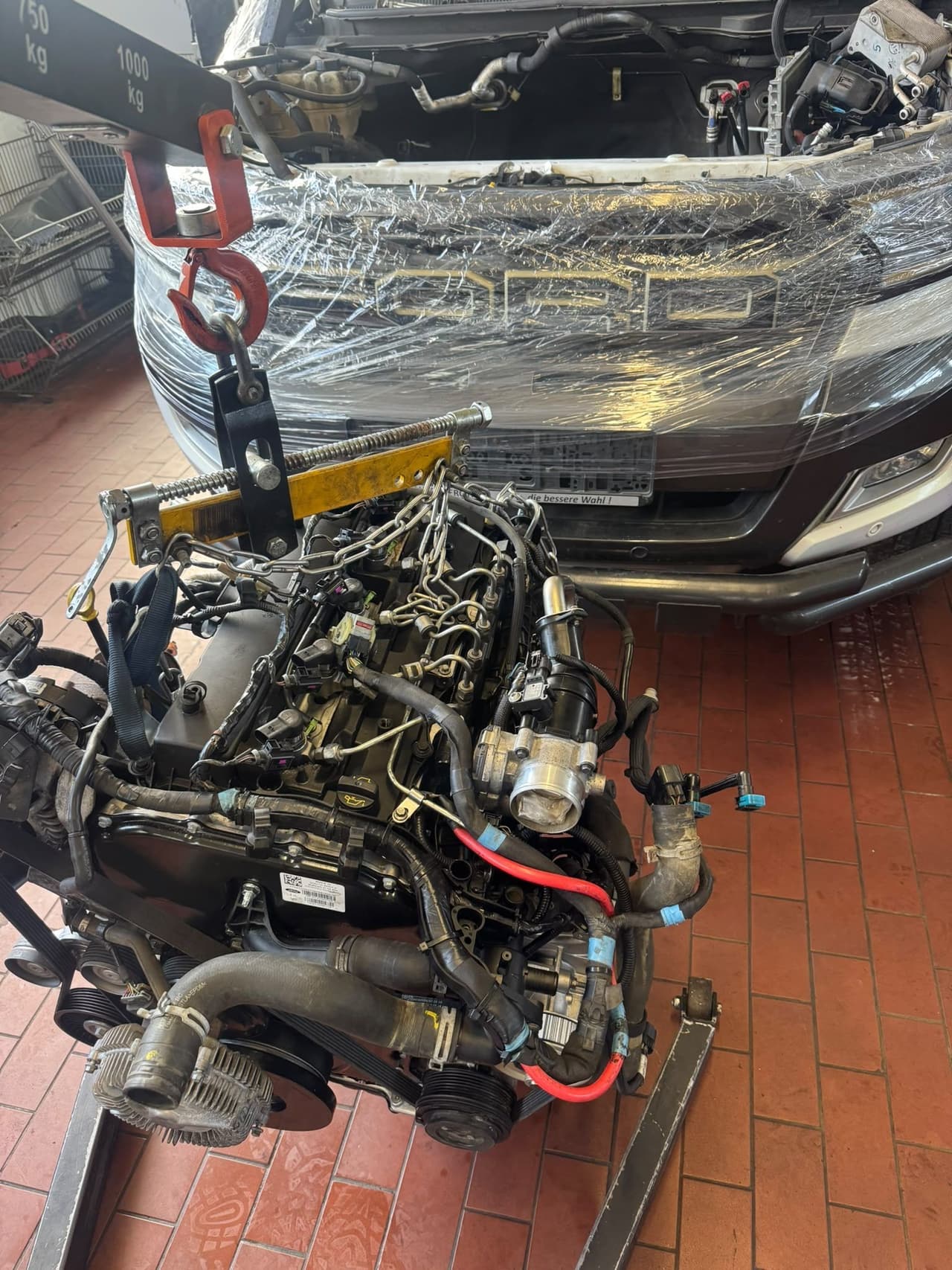 Ford-Ranger-Motor am Kran von oben, Kühlergrill des Fahrzeugs mit Folie geschützt