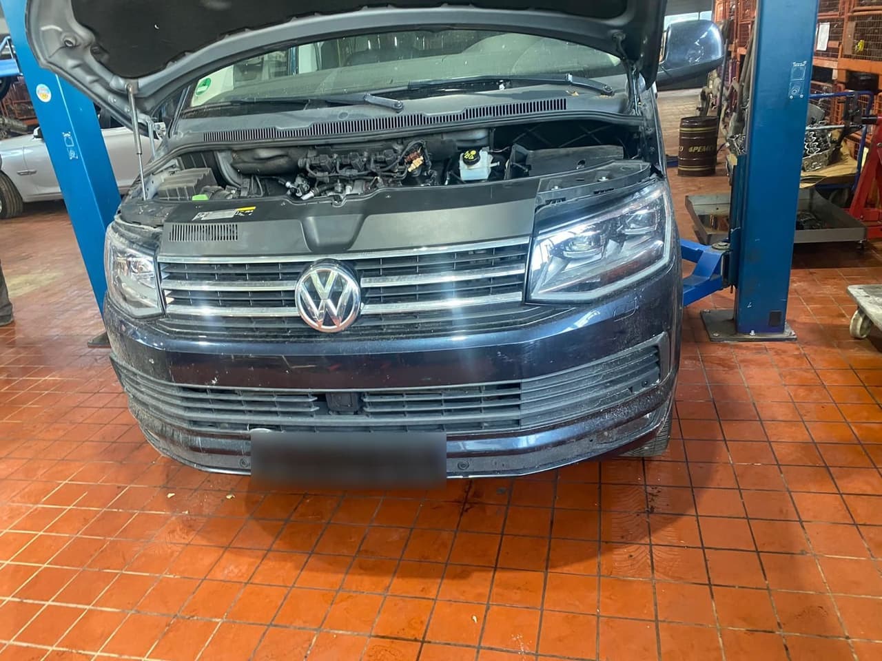 VW T6 mit geöffneter Motorhaube zwischen den Säulen der Hebebühne
